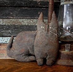 two gray cats sitting next to each other on a wooden shelf with a lamp in the background