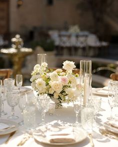 the table is set with white flowers and place settings for an elegant dinner or party