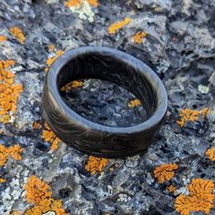 a black ring sitting on top of a rock covered in lichen