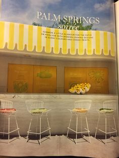 an open magazine with three white chairs and yellow awnings