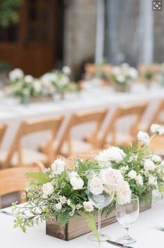 the table is set with white flowers and greenery