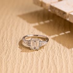 an engagement ring sitting on top of a table next to a piece of wood and a box