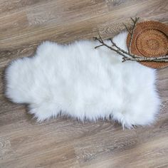 a white sheepskin rug with a straw hat on top of it next to a wooden floor