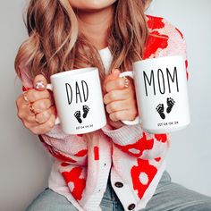 a woman holding two coffee mugs that read, dad and me