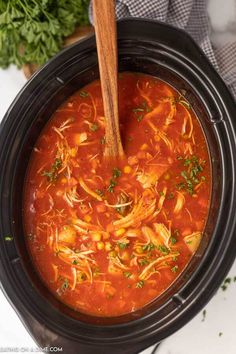 a crock pot filled with chicken tortilla soup and garnished with parsley