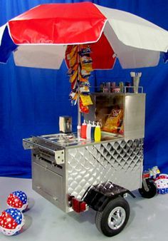 a silver cart with an umbrella and some snacks on the back is sitting in front of a blue backdrop