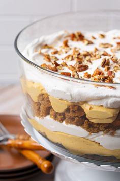 there is a large cake with white frosting and walnuts on top, in a glass dish