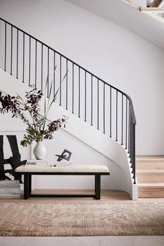 a vase with flowers on a table in front of a stair case and coffee table