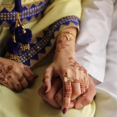 a close up of two people holding hands with hendi tattoos on their arms and fingers