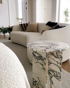 a marble table sitting in the middle of a living room next to a white couch