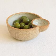 a small bowl filled with green olives on top of a table