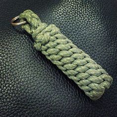 a green rope keychain on top of a black leather surface