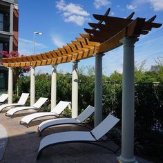 several lounge chairs are lined up on the side of a building with an attached pergoline