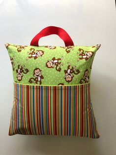 a green pillow with monkeys on it and a red handle hanging from the front side