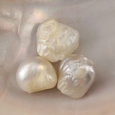 three different types of pearls sitting on top of a white cloth covered tablecloth with light shining in the background