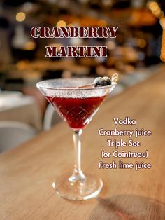 a drink in a martini glass sitting on top of a wooden table with the words cranberry martini written below it