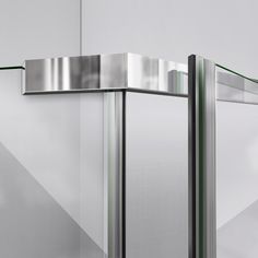 the corner of a glass and stainless steel shower door in an empty room with white walls