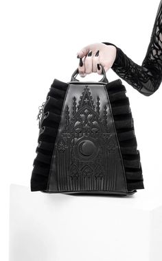 There's nothing quite as thrilling as a good flying buttress. Intricate black tonal embroidery depicts a Gothic cathedral and a large crescent, adding a mystical touch to the design Mesmerizing contrast of subtly shiny PU leather & deep black faux suede Faux suede ruffles exude elegance and romance Practical double zip main closure Convenient back zip pocket for quick-grab small items Side entry pockets hidden behind ruffles Silver crescent moon zipper pulls adorn the main opening, back pocket & Gothic Backpacks, Moon Backpack, Goth Purse, Flying Buttress, Gothic Purse, Midnight Moon, Suede Backpack, Gothic Bag, Attitude Clothing