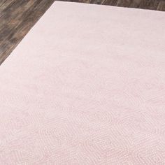 a pink rug with white polka dots on the floor and wooden floors in front of it