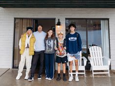 a group of people standing next to each other in front of a white brick building