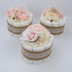 three wedding cake boxes with flowers on the top one is white and two are pink