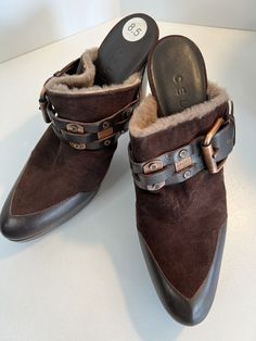 Elevate your shoe game with these stunning Celine mules. The luxurious brown leather and suede upper is accented with a gorgeous copper buckle, and the fur lining adds warmth and comfort for all-day wear. Slip on these high-heeled mules for a chic and contemporary look that's perfect for any occasion, whether it's a casual day out or a fancy party. These mules are brand new and come in their original box, with a block heel style and leather outsole for durability. With a pointed toe shape and slip-on closure, these shoes are easy to wear and will complement any outfit. Don't miss out on the chance to add these stylish Celine mules to your collection. Suede Mules With Buckle Closure And Open Heel, Brown Almond Toe Slip-on Mules, Suede Slip-on Mules With Buckle Closure, Brown Slip-on Mules With Stitched Sole, Brown Slip-on Mules With Buckle Closure, Shoe Game, Heeled Mules, Block Heels, Shoes Women Heels