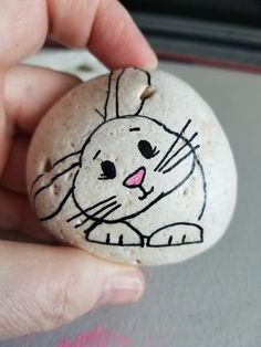 a hand holding a rock with a drawing of a rabbit on it's face