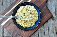 a bowl of macaroni and cheese with a spoon in it on a wooden board