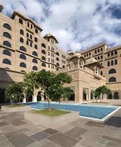 a large building with a pool in front of it and several trees on the other side