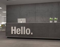 the front desk of an office with two laptops and plants in pots on it