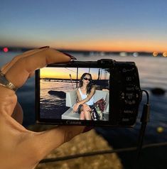 a person holding up a camera to take a photo on the beach at night time