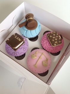 three cupcakes in a box with a judge's gaven on top