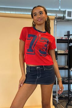 Also available in Olive and Black. Product Deets Red jersey mesh with navy number tee 100% polyester Navy trim detail Outlined 73 number graphic Full length baby tee fit Size small measures 17” long in front Runs true to size Model Info Kayleen is 5’6. Waist: 25" Bust: 32B Wearing size Small. Number Graphic, Number Shirt, Football Game Outfit, Red Jersey, Chic Winter Outfits, Jersey Style, Winter Outerwear, Cover Ideas, Street Style Winter