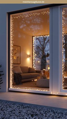 a living room with christmas lights on the windows and couches in front of it