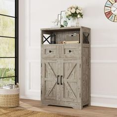 a wooden cabinet with doors and drawers in a living room next to a clock on the wall