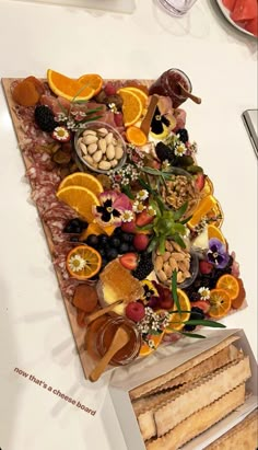 an assortment of fruits and nuts arranged on a cutting board next to some crackers