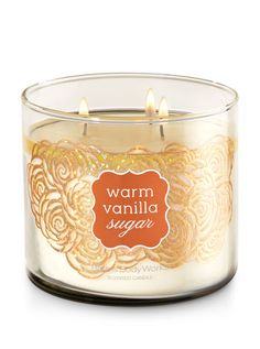 a glass candle with an orange label on the front and bottom, sitting in front of a white background