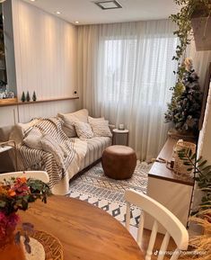 a living room filled with furniture next to a wooden table and white drapes on the windows