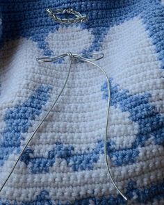 a crocheted blue and white blanket with a silver chain hanging from it's end