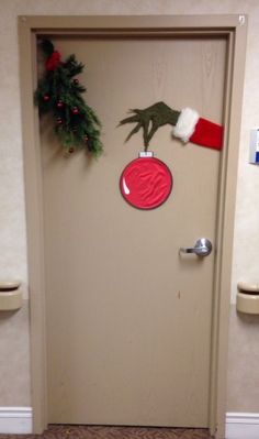 a door decorated for christmas with a santa hat and handprinted ornament