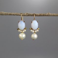 A pair of glowing large clover earrings set with an oval shaped opalite in copper bezel. Beautiful round pearls encircle the lower part of the opalite, and a single large pearl dangles down gently.   The hook is made of gold filled.  This unique design is timeless, so you can enjoy it for years and years to come and pass it on.  Measurements: Opalite in diameter: 10/14mm Total length including the hook: 3.5cm Materials: Stones: opalite, pearls Metal: gold filled, copper bezel  Since I use mostly natural gemstones, each jewel is unique and has its special, magical touch. Therefore, please expect subtle differences in color and form.  Click here for more earrings: https://www.etsy.com/shop/yifatbareket?ref=hdr_shop_menu§ion_id=5891684 TURNAROUND TIME & SHIPPING  This piece will be made withi Elegant Handmade Oval Pearl Earrings, Oval Opal Jewelry With Matching Earrings, White Oval Earrings For Wedding, Oval Opal Earrings For Formal Occasions, Elegant Handmade Oval Earrings, Oval White Pearl Earrings, Formal Oval Opal Earrings, White Oval Earrings With Ear Wire, White Oval Earrings