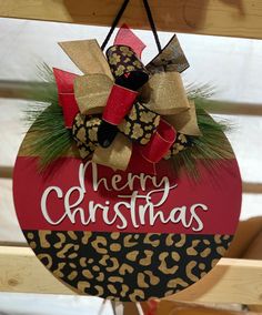 a merry christmas ornament hanging from a wooden door with leopard print and red ribbon