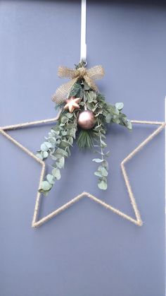 a star ornament decorated with greenery and baubles hangs on a door