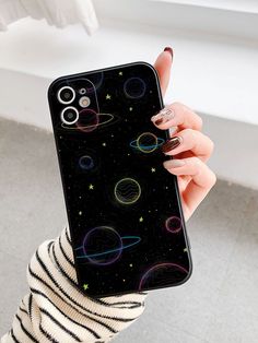 a woman holding up her phone case with an image of the planets and stars on it