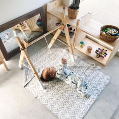 a baby laying on the floor in front of a mirror