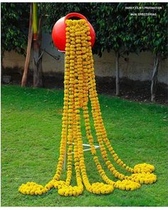 a bunch of yellow flowers are hanging from a pole in the grass next to a red ball