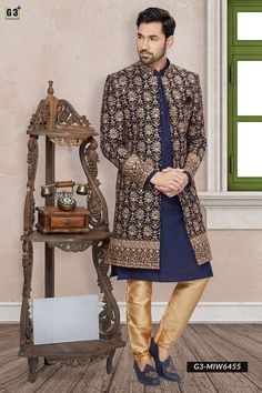 a man standing in front of a table with a clock on it and wearing an ethnic outfit