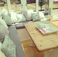 a living room filled with furniture and lots of pillows on top of a wooden table