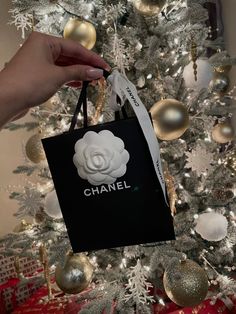 a chanel bag hanging from a christmas tree in front of a white and gold ornament