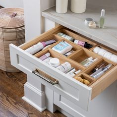 an open drawer in a white cabinet filled with cosmetics